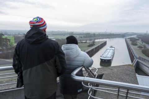 Onlookers look at a newly built tanker being manoeuvred by a push boat into Rothensee lock
