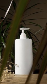A strand of natural dark hair for extensions with a bottle of care product