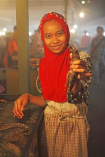Malaysian woman with headscarf showing a crayfish at Filipino night market