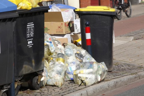 Blue bins for waste paper and yellow sacks and yellow bins for plastic waste standing on the street