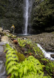 Hikers in front of a waterfall on a steep rock face