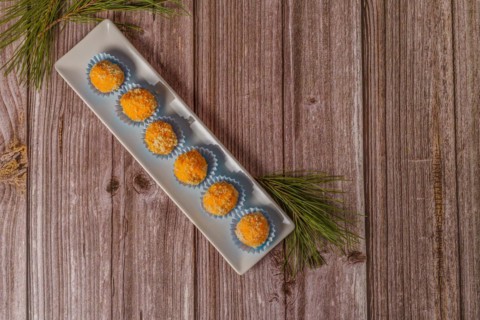 Sweet truffles in different flavors on a white ceramic tray on a wooden table