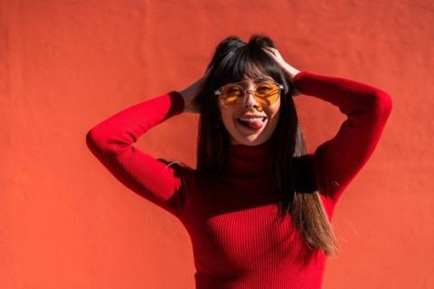 Posing brunette girl smiling in a dress and orange sunglasses in spring