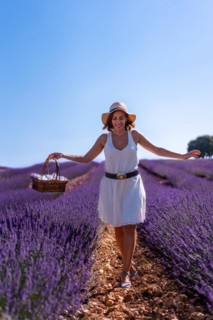 A caucasian woman in a summer lavender field with a hat picking flowers