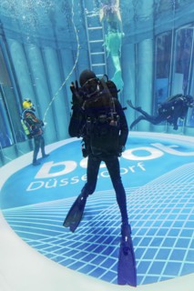 Divers swim in glass diving tower with logo