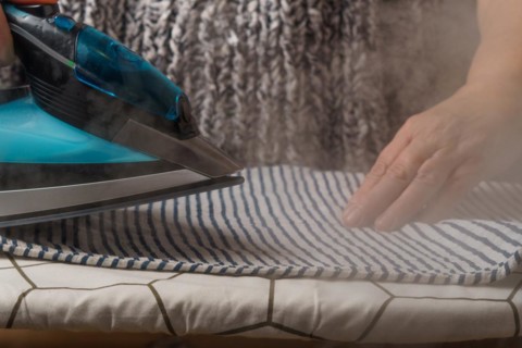 Woman ironing a striped T-shirt by steaming the iron