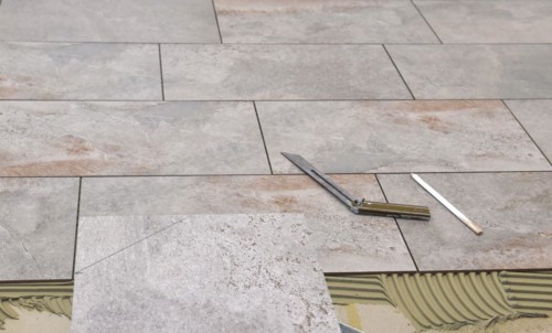 Tiler has applied tile adhesive and is sticking on new tiles