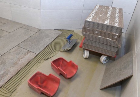 Tiler has applied tile adhesive and is sticking on new tiles