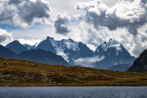 Mountain lake Lej Suvretta with Bernina group and Engadine mountains with cloudy sky
