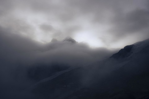 Summit of Piz Rosegg with Rosegg glacier and dramatic clouds at blue hour