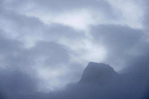 Peak of Piz Rosegg in dramatic clouds at blue hour