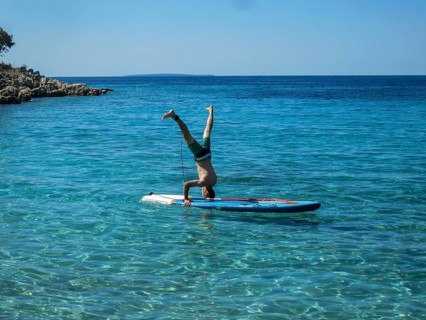 Man doing headstand on a SUP in crystal clear water