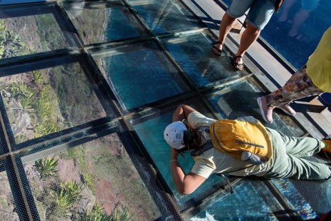 Tourist looks through the glass floor 580 metres into the depths
