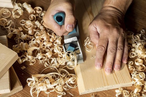Carpenter working wood surrounded by sawdust