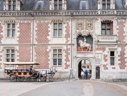 Equestrian statue of Louis XII above the entrance to the Chateau Royal de Blois and a carriage with two white horses