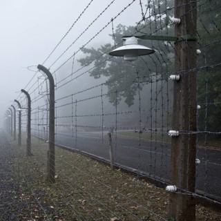 Reconstructed camp fence with crematorium in the fog at beech forest concentration camp