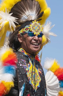 Adult First Nations man at a pow wow wearing colorful regalia