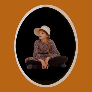 Girl in dress with pigtails and hat sits on the ground. With oval frame and text freedom
