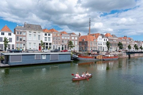 Canoe in front of historic house facades and houseboats at Londensekaai