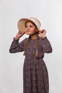 Portrait of a girl holding her sun hat tightly against a white background