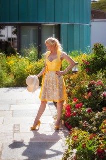 Blonde woman in a yellow dirndl in front of a sea of flowers