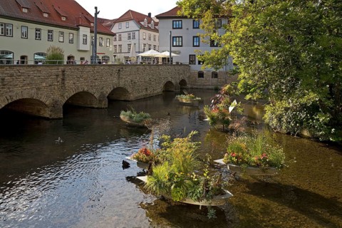 Zinc tubs in the shape of boats with flowering plants on the river Gera