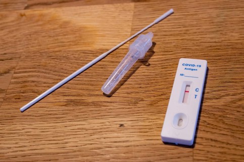 Close-up of a negative Corona rapid test cassette with collection swabs and test liquid on a wooden table