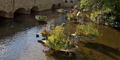 Zinc tubs in the shape of boats with flowering plants on the river Gera