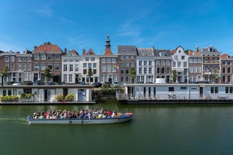 Tour boat in front of historic house facades and houseboats at Londensekaai