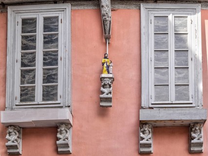 Detail of a house in the old town with figures under and between the windows
