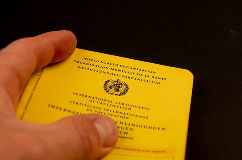 Hand holding a German vaccination certificate against a black background