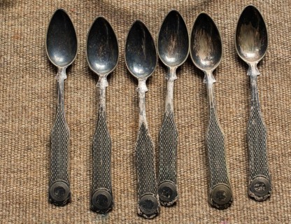 Stylish steel teaspoons on a textured background in display