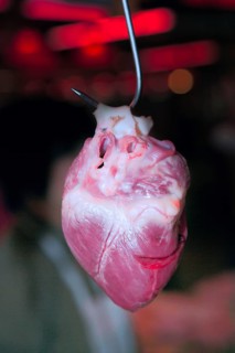 A pig's heart hangs on a hook at a meat counter