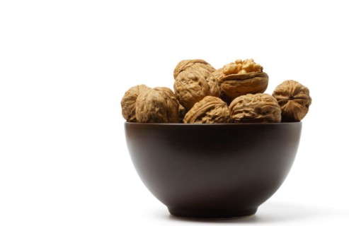 Walnuts in a brown bowl isolated on a white background
