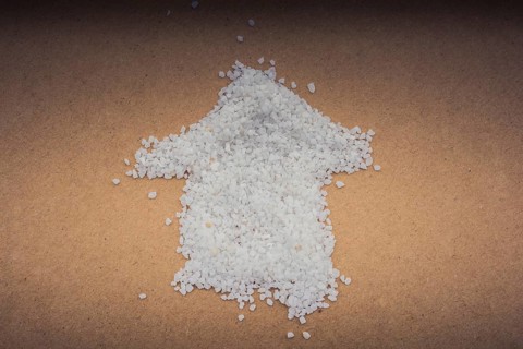 Arrow formed by some white sand on brown paper
