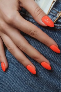 Bright neon manicure on female hands on the background of jeans. Nail design. Beauty hands