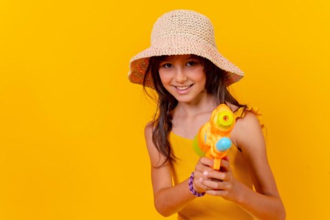Portrait of a girl playing with a water gun on summer vacation