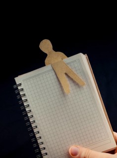 Man shape cut out of paper in notebbok in hand