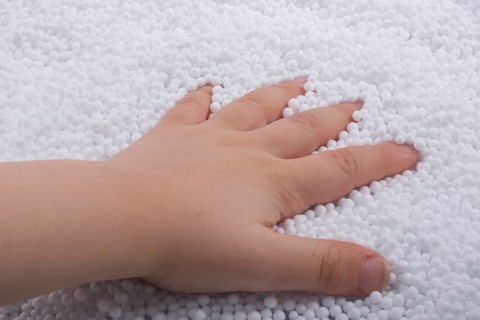 Toddler hand in White polystyrene foam balls as background