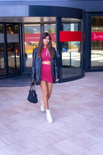 Portrait of a Caucasian girl in a red dress walking out of the revolving door of the shopping center