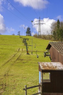 Ski lift at standstill due to lack of snow caused by climate change at the end of winter on a hill in Muensingen