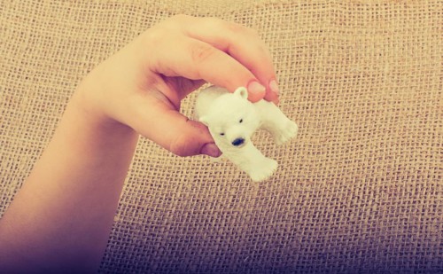 Hand holding a Polar bear model in hand on canvas