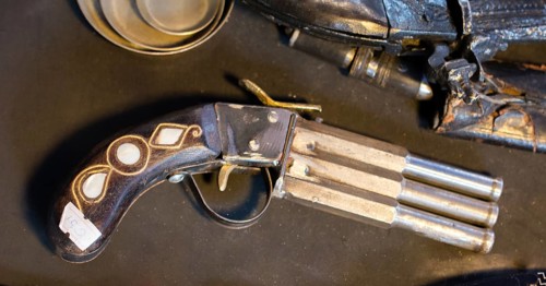Antique stylistic revolve-like gun on a wooden background