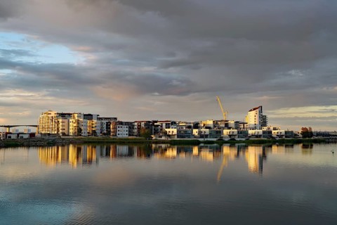 Modern apartment buildings and cranes reflected in the calm Baltic Sea