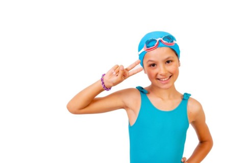 Portrait of girl with swimsuit and diving goggles for swimming lessons in the pool making the victory symbol. White background