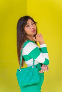 Portrait of a Caucasian girl in a white striped sweater on a green background