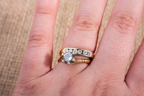 Hand wearing a fake diamond ring on a textured background
