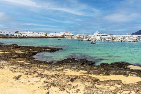 Beach and port with boats and ferries in Caleta del Sebo