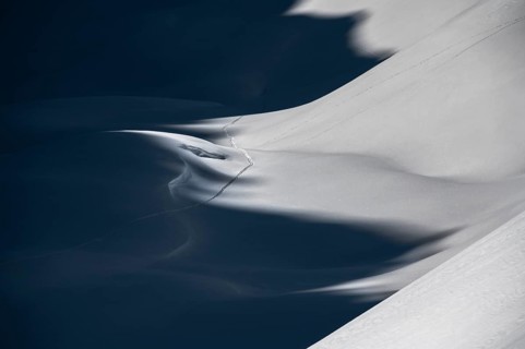Ski touring trail in deep snowy mountain landscape with light and shadow