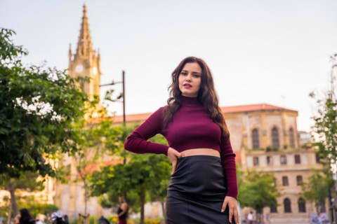 Portrait of a brunette model with a leather skirt next to a church visiting the city